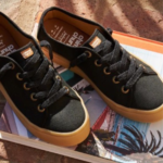 Zapatillas urbanas de lona negra con suela de goma caramelo marca Chimmy Churry sobre un libro