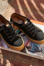 Zapatillas urbanas de lona negra con suela de goma caramelo marca Chimmy Churry sobre un libro