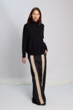 Mujer vestida con una polera larga con hombros caidos de suave textura en color negro