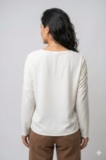 Remera mujer modelo Copernico color blanqucino, calce súper oversize en tela crepé, con detalle de mangas fruncidas y hombros caídos, fotografiada en una calle empedrada de Buenos Aires.