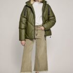 Modelo vistiendo campera puffer Gaiman verde oliva con capucha, remera blanca y pantalón wide leg beige