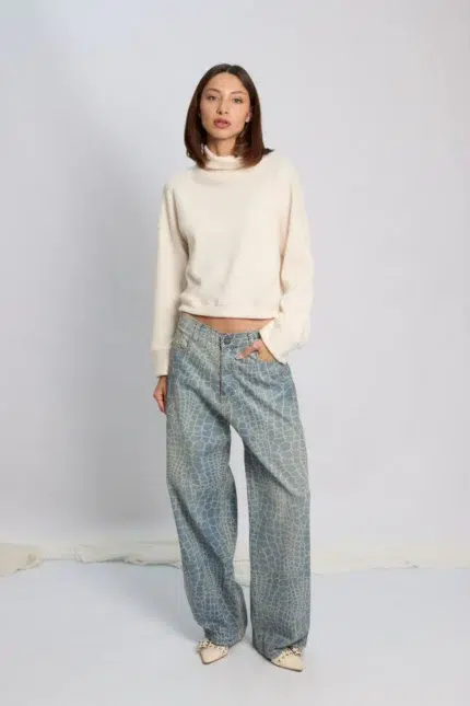Modelo posando con Jean wide leg Roy con estampa animal print croco y polerón color crudo.