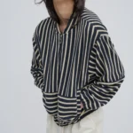 Campera bomber rayada azul marino y crudo en tejido de punto oversize combinada con pantalón claro.