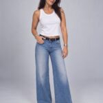 Modelo vistiendo Jean Loto Vanesa Petris wide leg azul con ruedo deshilachado y musculosa blanca